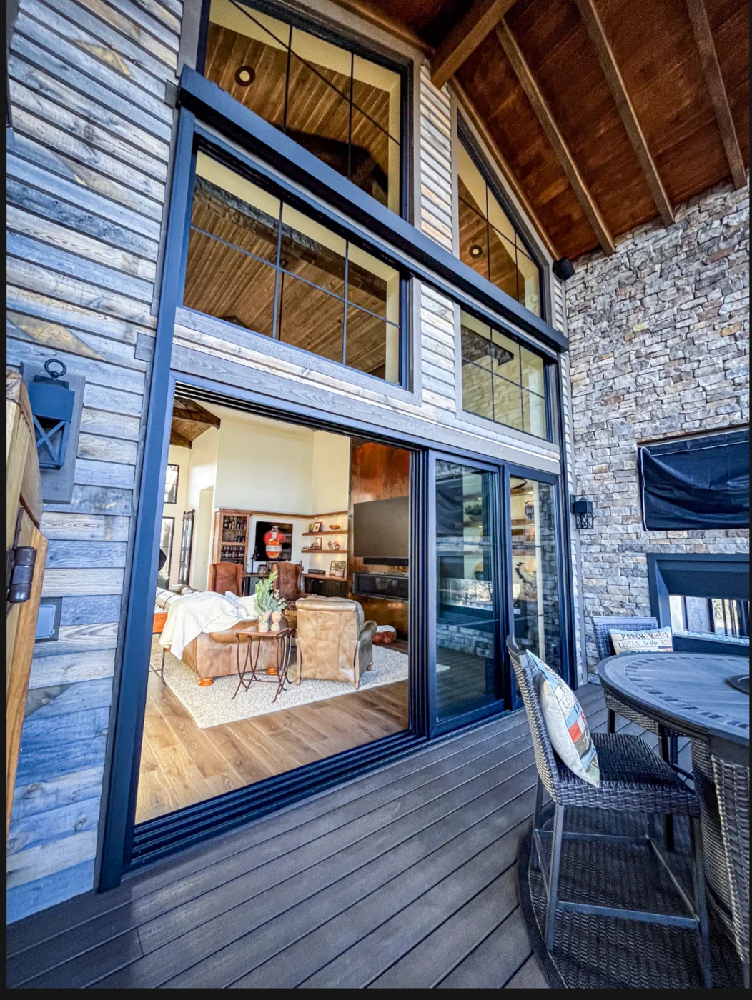Two-story glass wall and sliding opening beneath a timber roof at Talking Rock